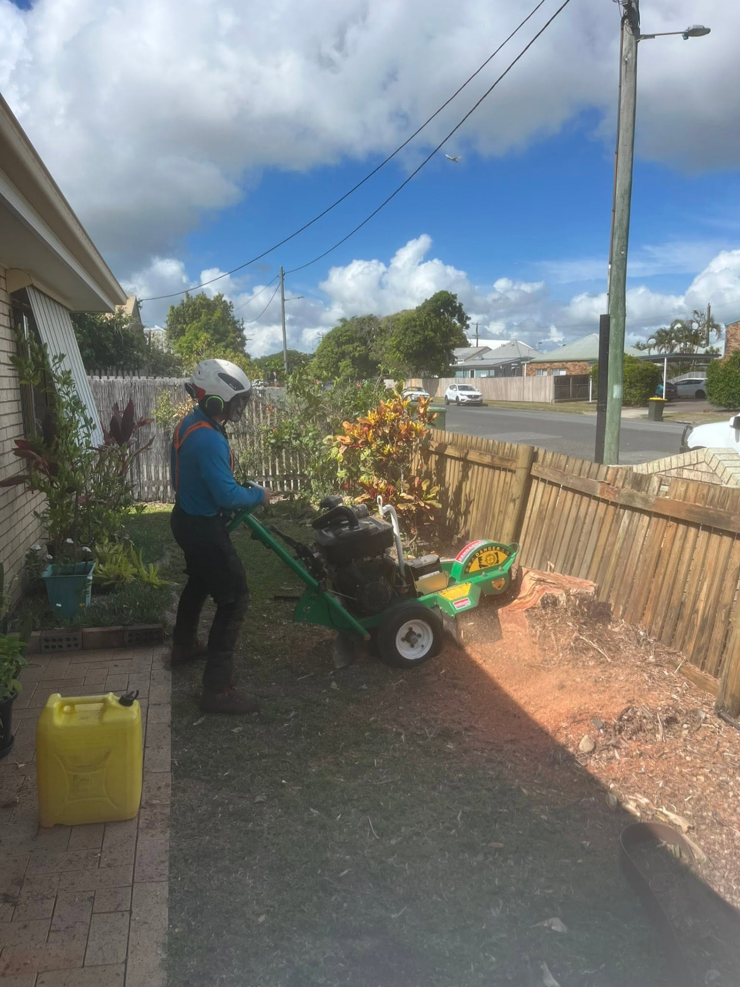 Operator using a stump grinder to remove a tree stump in a Mackay front yard