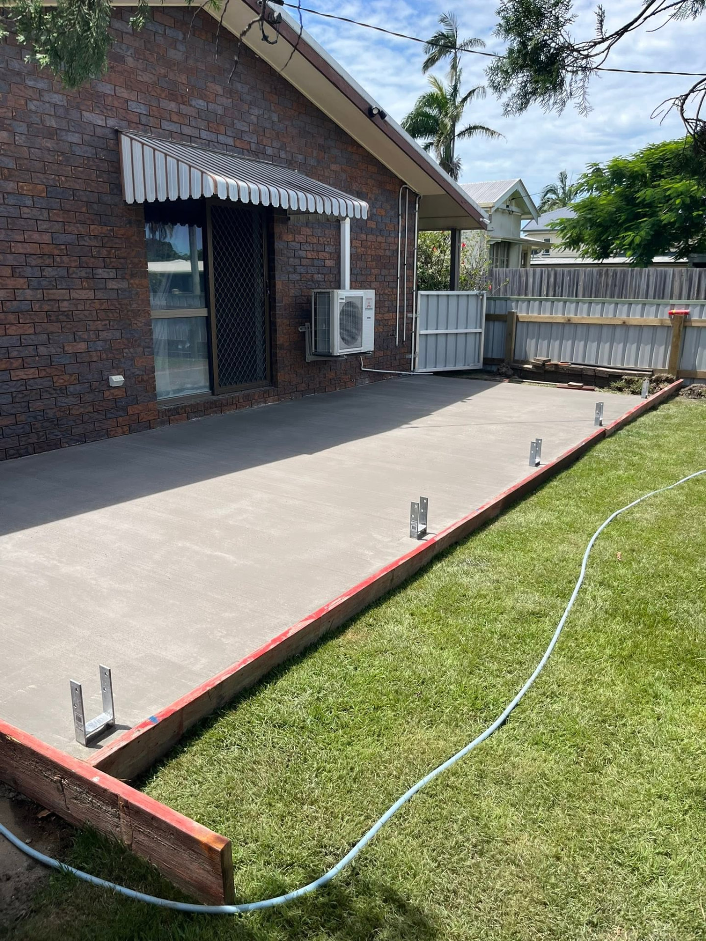 Finished concrete slab next to a brick house with green lawn alongside